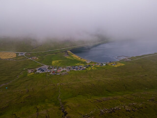 Beautiful aerial view of the town of Miovagur in the Faroe Islands, with its :churchs, grass roofs and colorful Houses in front of the ocean 