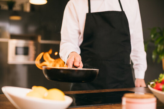 Confident chef with burning frying pan 