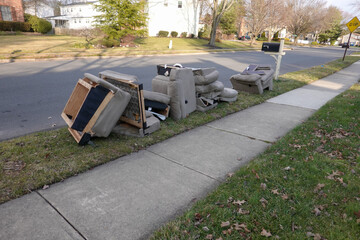 Old disassembled chairs and cushions lined up by the curb waiting to be disposed of by the garbage...