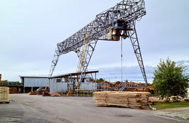 Industrial warehouse timber mill, finished products on a sawmill outdoors. Timber loading Gantry...