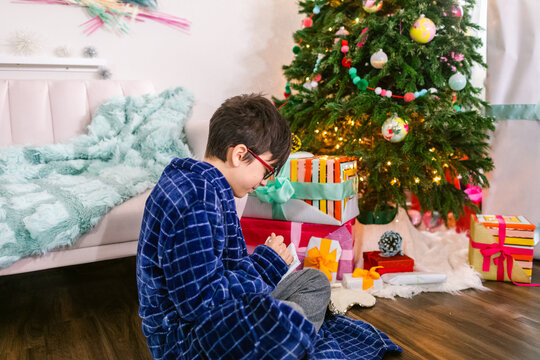 Boy making wish near Christmas tree