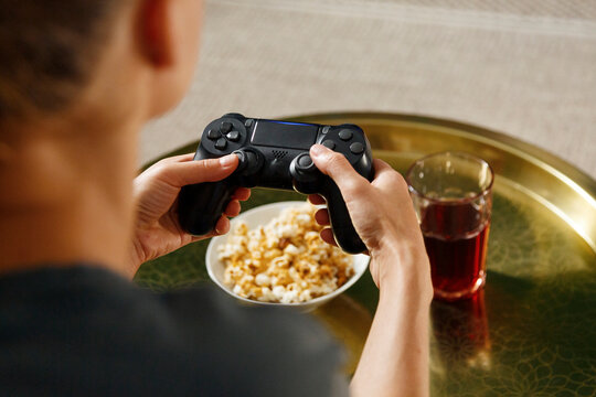 Crop female gamer playing video game over table