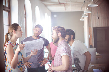 Casual business people reviewing paperwork in meeting in office