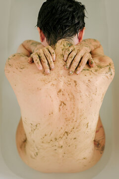Naked woman apply natural herbal mask to her back 