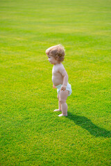 Baby toothache at the park on a sunny day. Beautiful blonde hair male toddler outdoors.