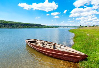 Old wooden boat moored on the shore . Green riverside in the springtime