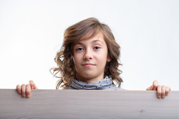 Young girl looking over the top of a wooden board with a smile