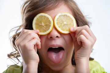 Mischievous little girl holding sliced lemons to her eyes