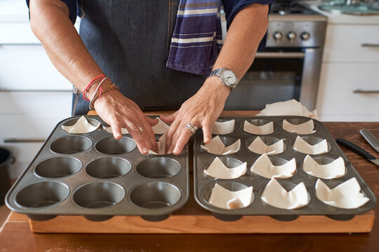 Homecook laying pastry into muffin pan