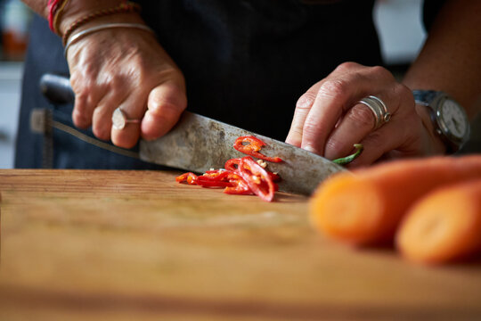 Home Cook Slices A Red Chilli Pepper On Chopping Board