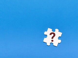 Question mark concept icon on wooden jigsaw puzzle against blue background.