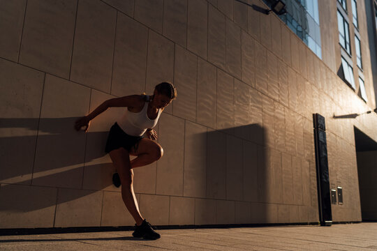 Woman stretching against a wall 