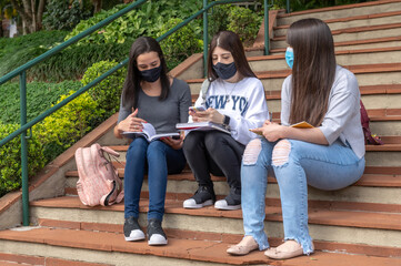 Fototapeta premium university students wearing protective masks, with backpacks and chatting outside at a sunny day