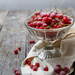Frozen red currants in a glass vase on a cloth on a rustic wooden table. Close-up.
