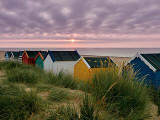 sunrise over brightly coloured beach huts