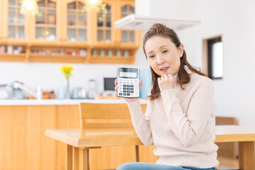 電卓を持つシニア女性　考える