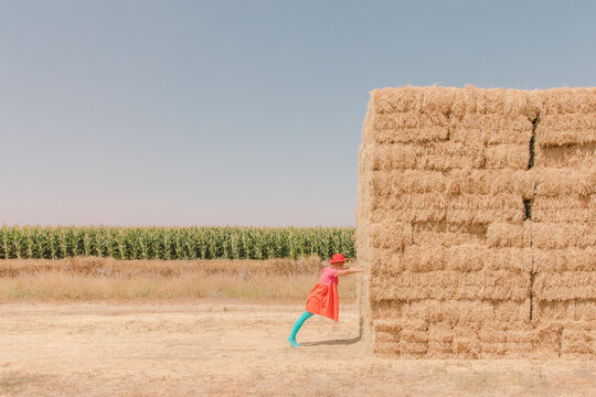 Girl pushes hay stack