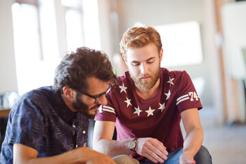 Smiling casual businessmen using digital tablet in bean bag chair