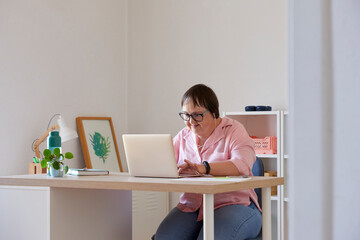 Glad woman with Down syndrome browsing laptop