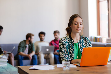 Smiling creative businesswomen working at laptop in office