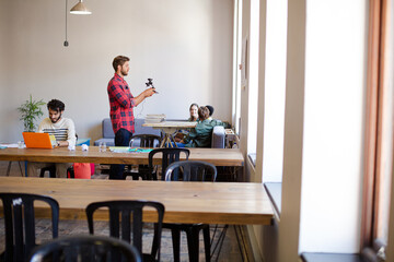 Creative businessman posing photograph for coworker instant camera in office