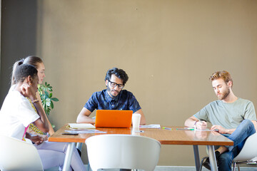 Creative business people working at tables in sunny office