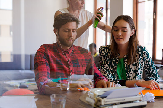Creative writer with headphones using typewriter in office