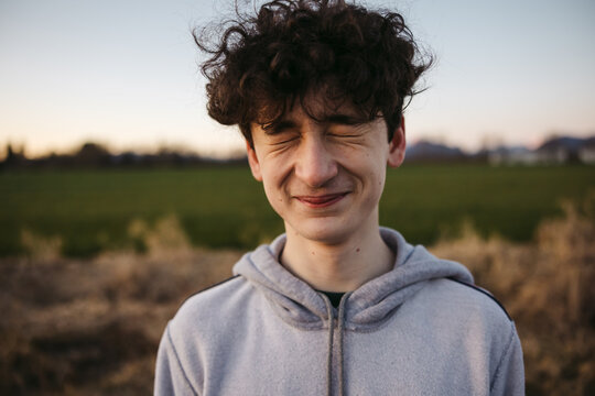 Squiting teenage boy outside.