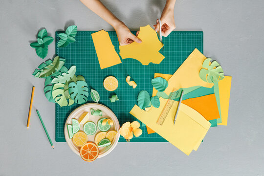 Flatlay with woman's hands making leaves and fruits papercraft