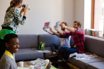 Creative business people playfully posing for coworker instant camera