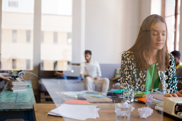 Creative businesswoman reviewing paperwork at typewriter in office