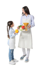Young mother and daughter with fresh products on white background