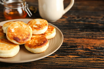 Plate with tasty cottage cheese pancakes on table