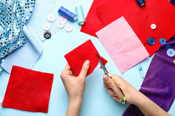 Woman cutting felt on color background