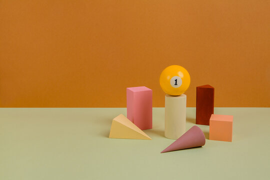 Different wooden forms with billiard ball on paper background