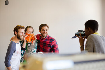 Creative business people playfully posing for coworker instant camera
