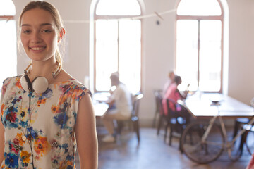 Portrait smiling casual businesswoman headphones in sunny open office