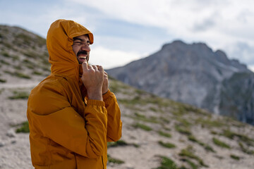 Man closing his rain jacket  on a mountain trail