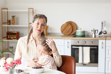 Little girl and her mother having breakfast in kitchen