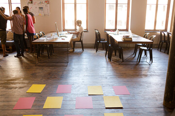 Casual business people raising hands in circle in sunny office meeting