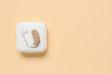 Box with hearing aid on color background