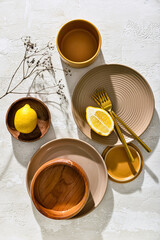 Different tableware and lemon on white background