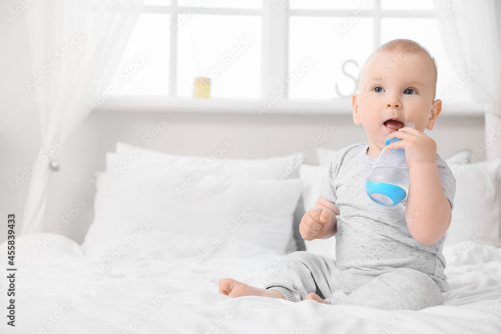 Poster Cute little baby with bottle of water in bedroom