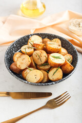 Plate with baked potatoes and rosemary on light background