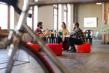 Creative business people working behind bicycle wheel in office