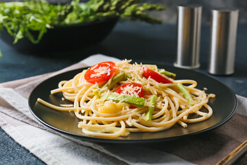 Plate of tasty pasta with vegetables and cheese on dark background
