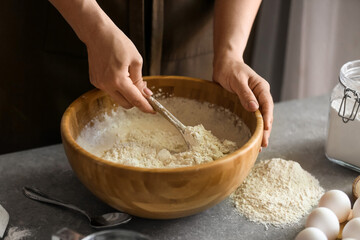 Female chef preparing dough on kitchen table, closeup