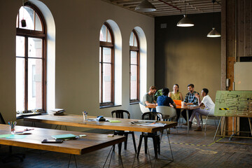 Creative business people working at tables in sunny office