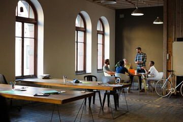 Creative business people working at tables in sunny office