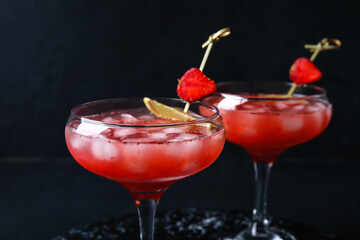 Glasses of tasty strawberry margarita on dark background, closeup